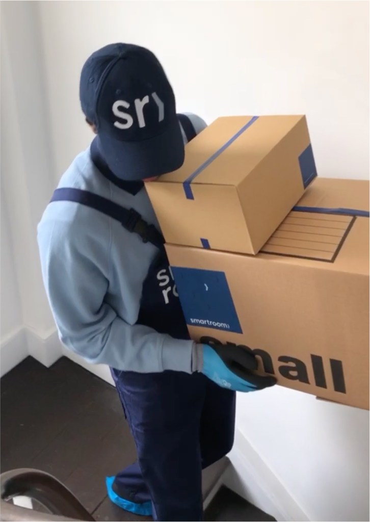 Smartroom movers packing items into a cardboard box for self storage in London.